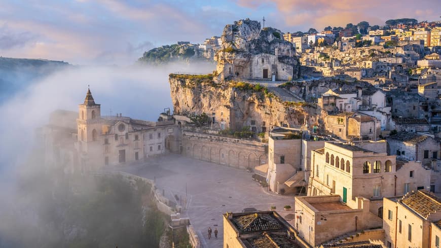 Matera sieht im Morgennebel richtig mystisch aus. Ein Blick auf Matera mit vielen beigefarbenen Häusern und Nebel drum herum.