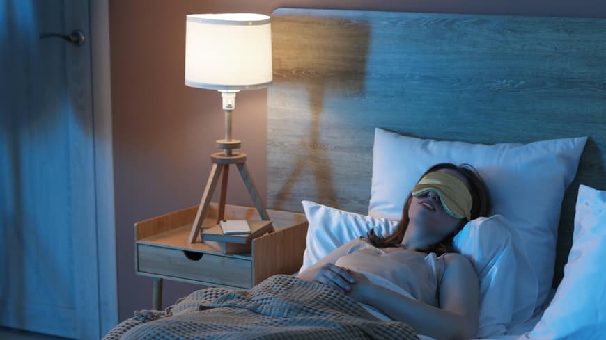 Frau schläft im Bett mit Schlafmaske