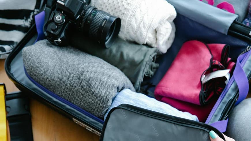 Voller Koffer mit Kleidung, Kamera und Sortierfächern.