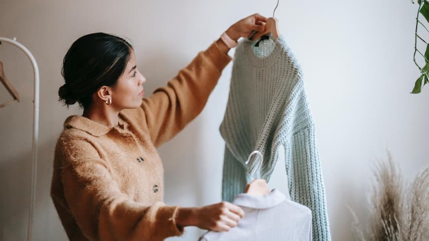 Eine junge Frau sortiert Kleidung aus