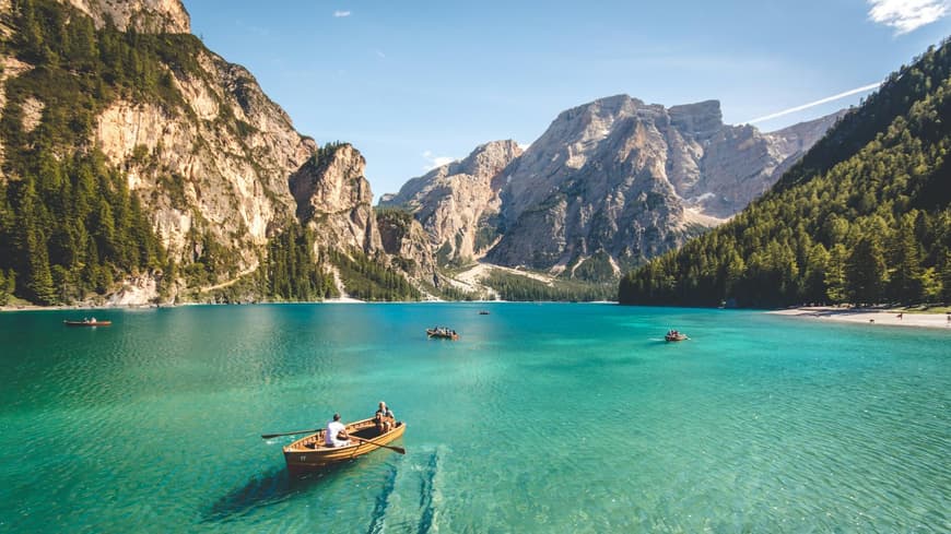 Ein großer See mit Gebirge im Hintergrund und ein paar Booten auf dem Wasser.