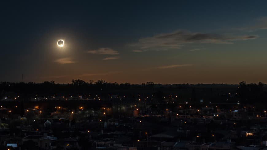 Totale Sonnenfinsternis über den Dächern einer Stadt.