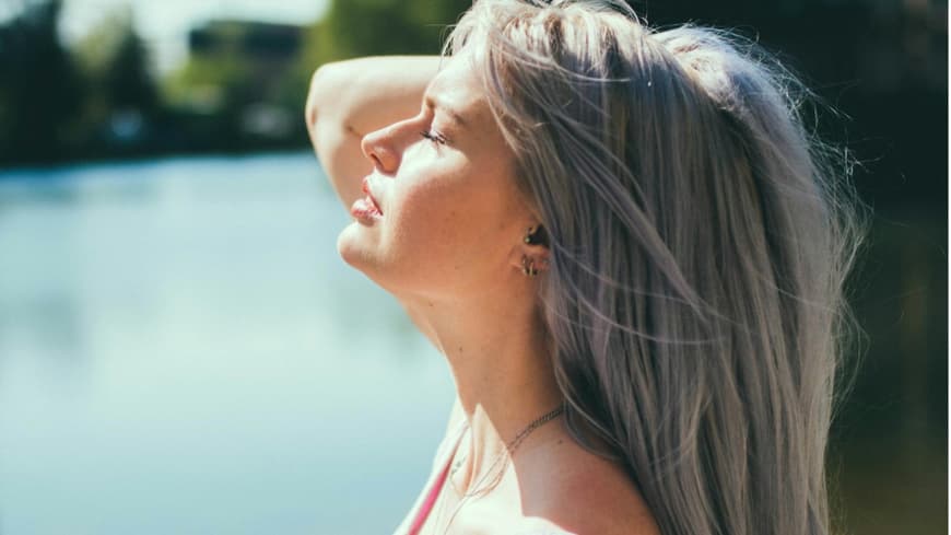 Eine Frau hält ihr Gesicht in die Sonne