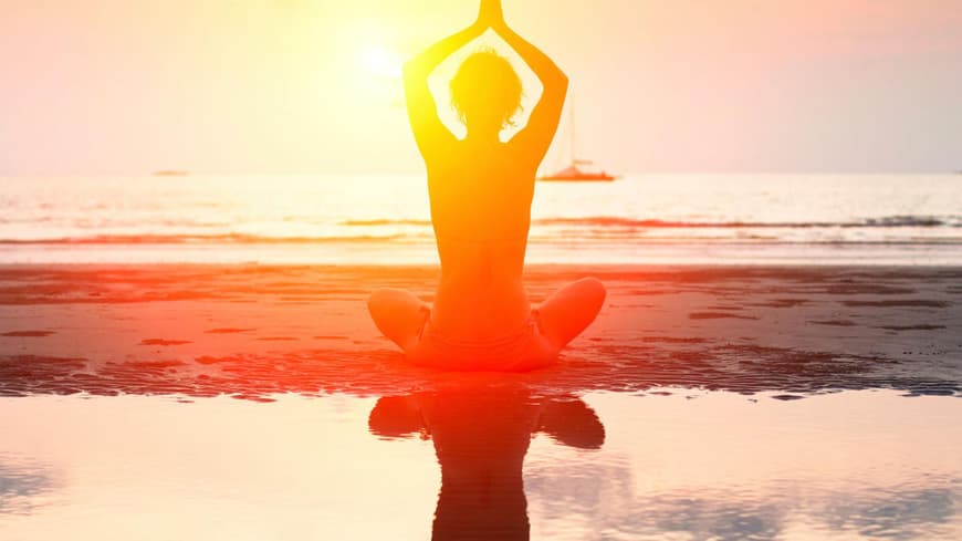 Frau macht Yoga am Strand.