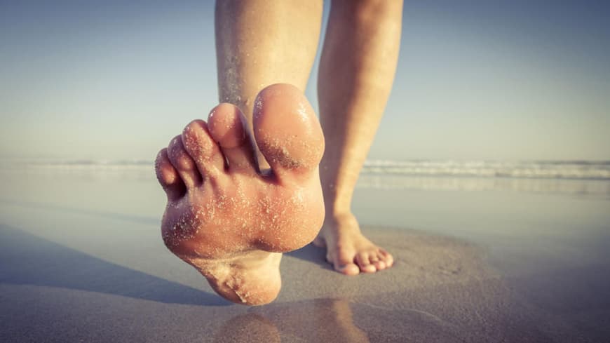 Frau barfuß am Strand