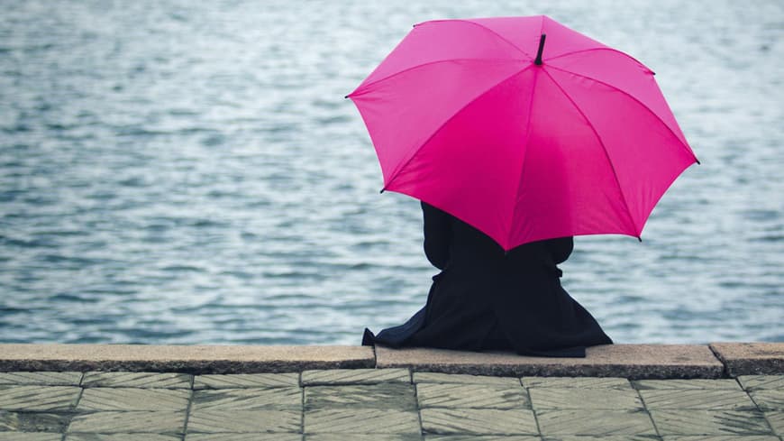 Frau mit Regenschirm am See