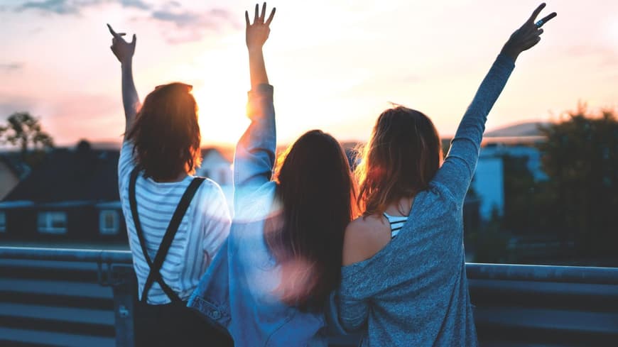 Drei Frauen heben die Arme in die Luft.