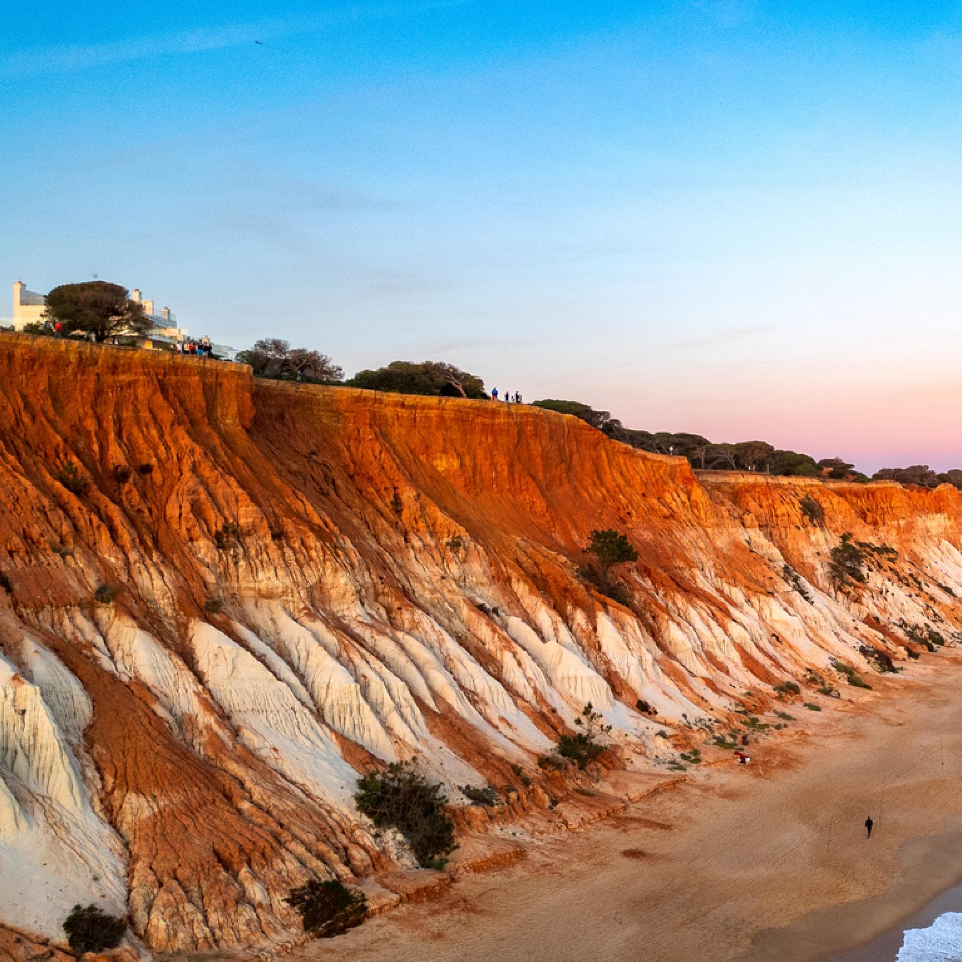 Rötliche Klippen und blaues Meer an der Praia da Falésia in Portugal.