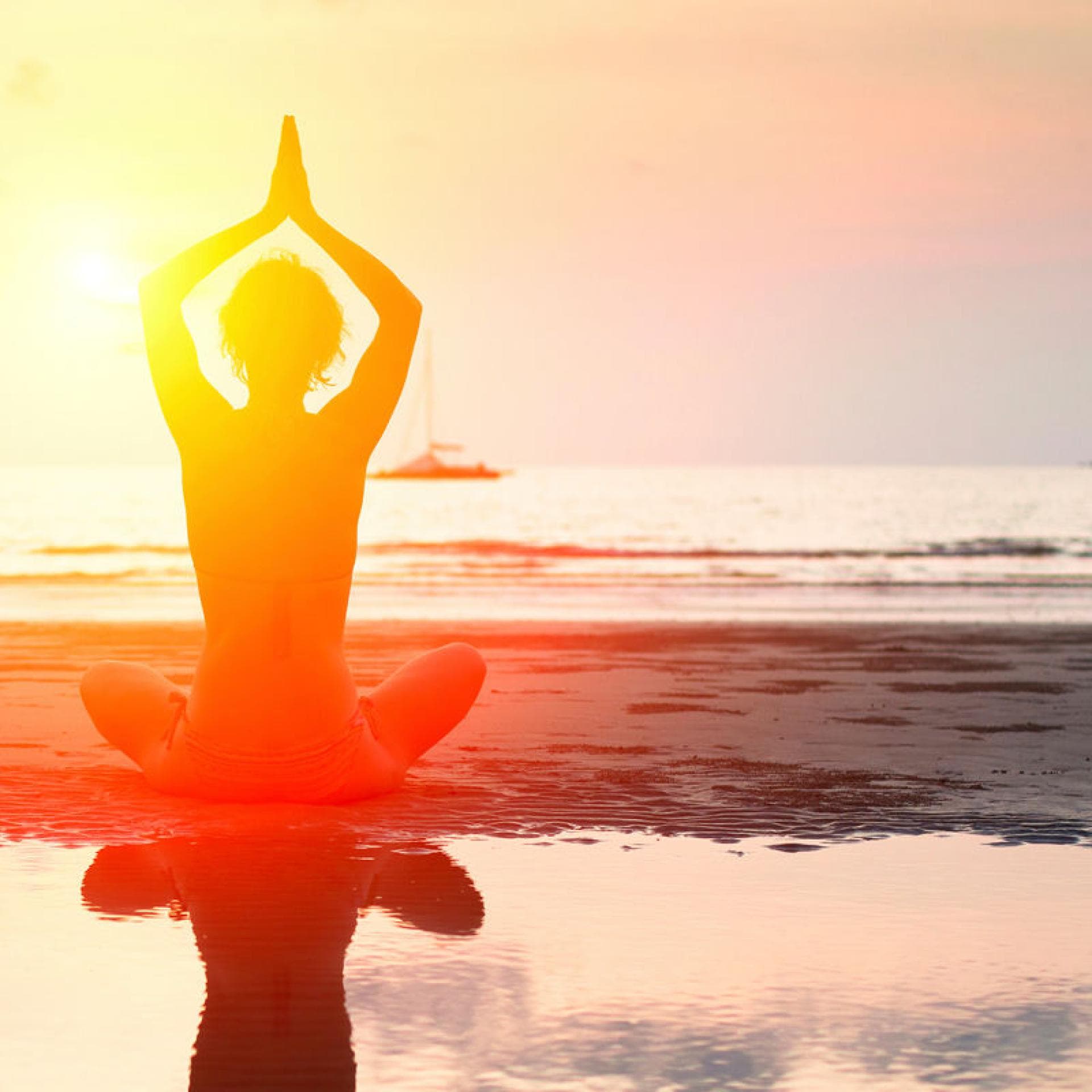 Frau macht Yoga am Strand.