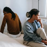 Was tun, wenn man den Partner nicht mehr anziehend findet? Mann und Frau sitzen mit dem Rücken zueinander auf einem Bett