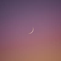 Neumond am rosa-orangefarbenen Himmel