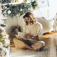 Frau liest ein Buch unter dem Weihnachtsbaum.