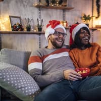 Glückliches Paar sitzt auf der Couch und guckt einen Weihnachtsfilm