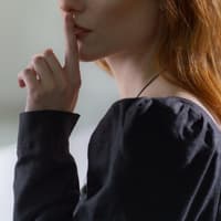 Schweigen statt Reden Frau hält ihren Zeigefinger vor ihren Lippen