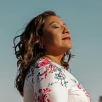 Frau guckt mit geschlossenen Augen zum Himmel