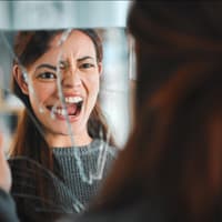 Frau schaut in zerbrochenen Spiegel