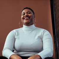 Selbstbewusste Frau mit kurzen Haaren lächelt in die Kamera