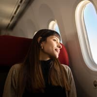 Frau sitzt im Flugzeug und guckt aus dem Fenster