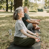 Älteres Paar macht Yoga auf einer Wiese.