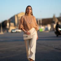 Frau trägt beigefarbene Handtasche Frau trägt beigefarbene Handtasche