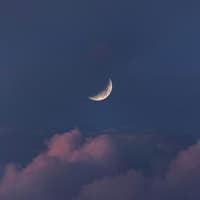 Halbmond am Himmel über den Wolken