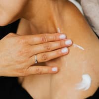 Retinol Bodylotion Frau cremt sich mit Bodylotion ein