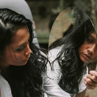 Psychologie Frau schaut sich im Spiegel an