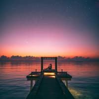 Wochenhoroskop Frau sitzt unter Sternenhimmel am Steg