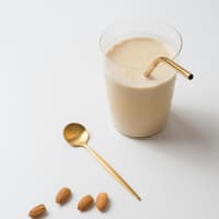 Der Sheko Shake für Well-Aging besteht aus Kollagen und Proteinpulver. Ein cremiger Shake im Glas mit goldenem Strohhalm.