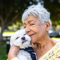 Frau schmust mit einem weißen kleinen Hund.