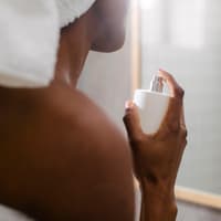 Frau sprüht nach dem Duschen Parfum auf.