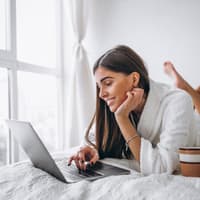 Frau auf dem Bett am Laptop