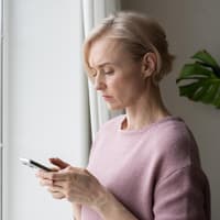 Frau guckt skeptisch auf ihr Handy.