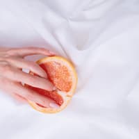 Zitrusfrucht liegt auf einem weißen Tuch und eine Hand fasst herein.