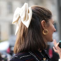 Frau mit Bob trägt Schleife im Haar.