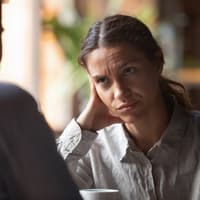 An diesen Anzeichen erkennst du einen schlechten Menschen. Frau blickt kritisch auf ihren Gesprächspartner.
