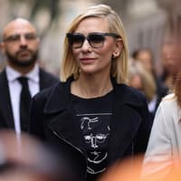 Frau mit blonden kurzen Haaren, seitlichem Scheitel und Sonnenbrille.