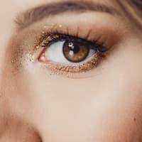 Silvester-Make-up ist vor allem glitzernd. Frau trägt ein glitzerndes Augen-Make-up.