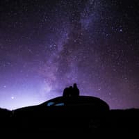 Welche Sternzeichen jetzt endlich ihre Einsamkeit hinter sich lassen können, erfährst du hier. Pärchen sitzt auf Autodach und schaut in den Sternenhimmel
