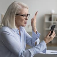 Frau liest etwas auf dem Handy und beschwert sich.