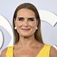 Brooke Shields mit Perlen Ohrringen und einem gelben Kleid.