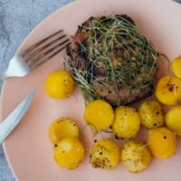 Kartoffeln und Fleisch auf einem rosanen Teller.