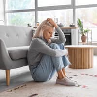 Frau sitzt traurig am Boden