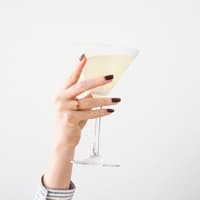 Frauenhand mit Nagellack hält Sektglas