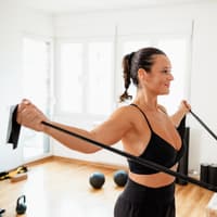 Frau strecht ihren Körper mit einem elastischen Band.
