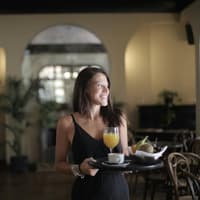 Frau mit einem Tablett und einem Glas Orangensaft und Obst.