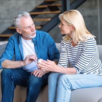 Mann und Frau sitzen auf einer hellen Coach und führen ein Gespräch.