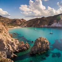 Das Meer an der Küste der Insel Milos mit zwei Segelbooten drauf.