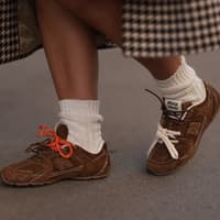 Das sind die Sneaker-Trends 2025. Frau in braunen Sneakern