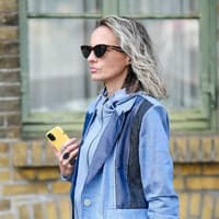 Ältere Frauen mit grauen Haaren, Sonnenbrille und einem Jeansmantel.